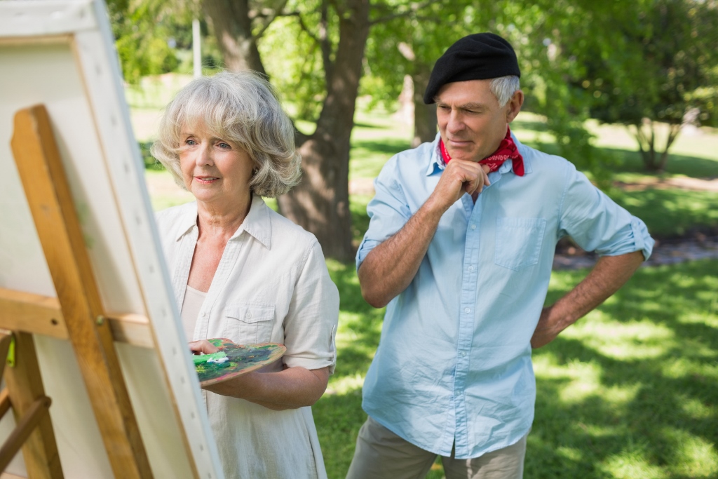 Man watching mature woman paint in park